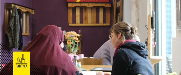 Zwei Frauen sitzen an einem Tisch und unterhalten sich.