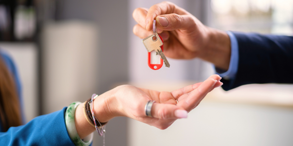 Eine Hand gibt einen Schlüssel in eine andere Hand.